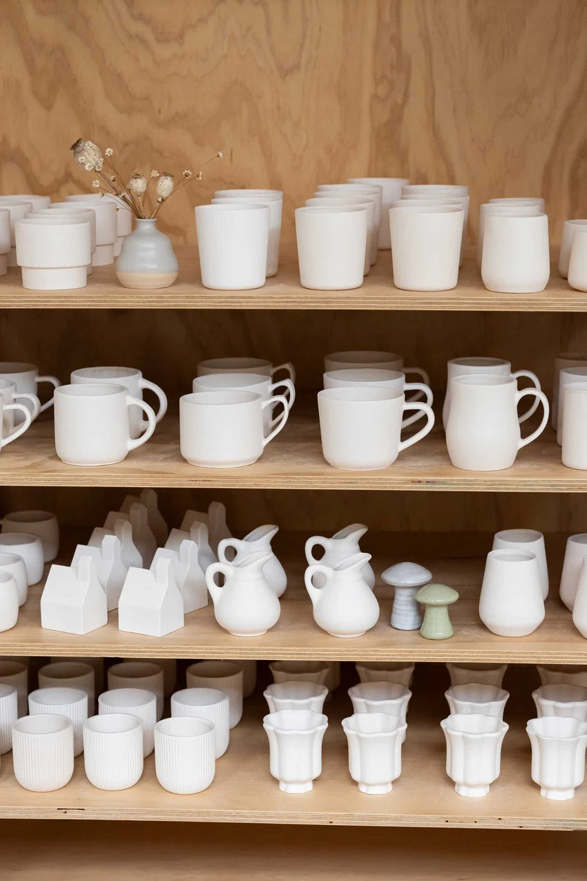 Shelves of unpainted mugs, bowls and vases to choose from